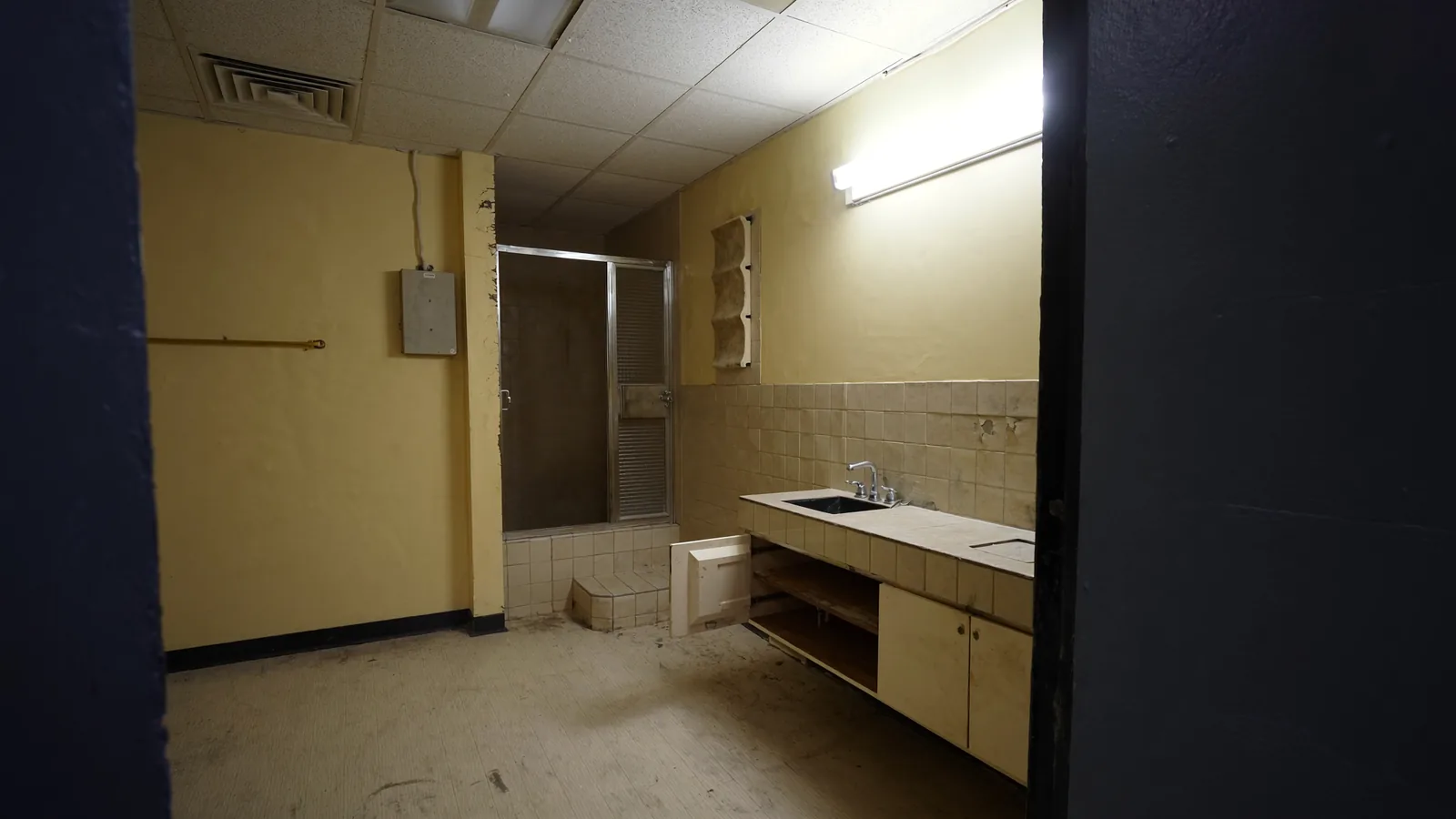 Original 1950s Renton bathroom before renovation — cast-iron tub, worn tile floor, and dated fixtures
