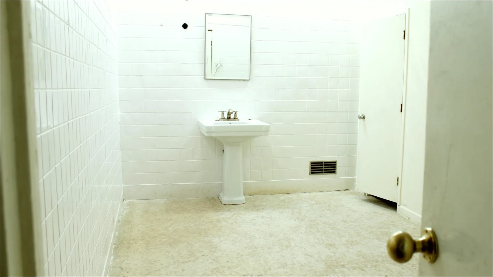 Original 1920s Tacoma bathroom before renovation — cast-iron tub, cracked hex tile floor, and dated fixtures